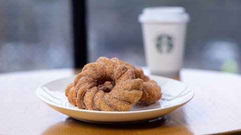 Two donuts on a plate with a Starbucks coffee in the background